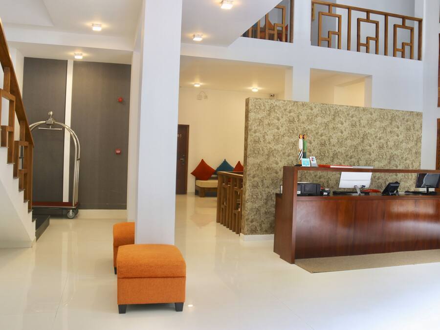 Eine moderne Hotelhalle mit einem Holzbüro, einer Sitzecke mit bunten Kissen, einer Treppe und einer großen Wand mit einem dekorativen Muster.