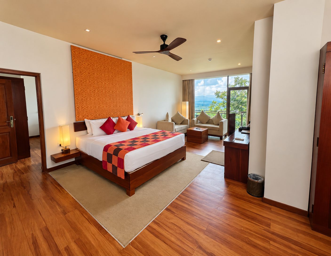 Habitación de hotel con una cama grande, un escritorio, una silla, un sofá, un ventilador de techo y vistas al exterior.