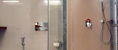 A modern bathroom with a glass-enclosed shower, a white toilet, and a marble-tiled floor.