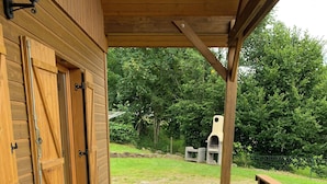 Una terraza de madera con una mesa dispuesta para cuatro personas, rodeada de sillas.
