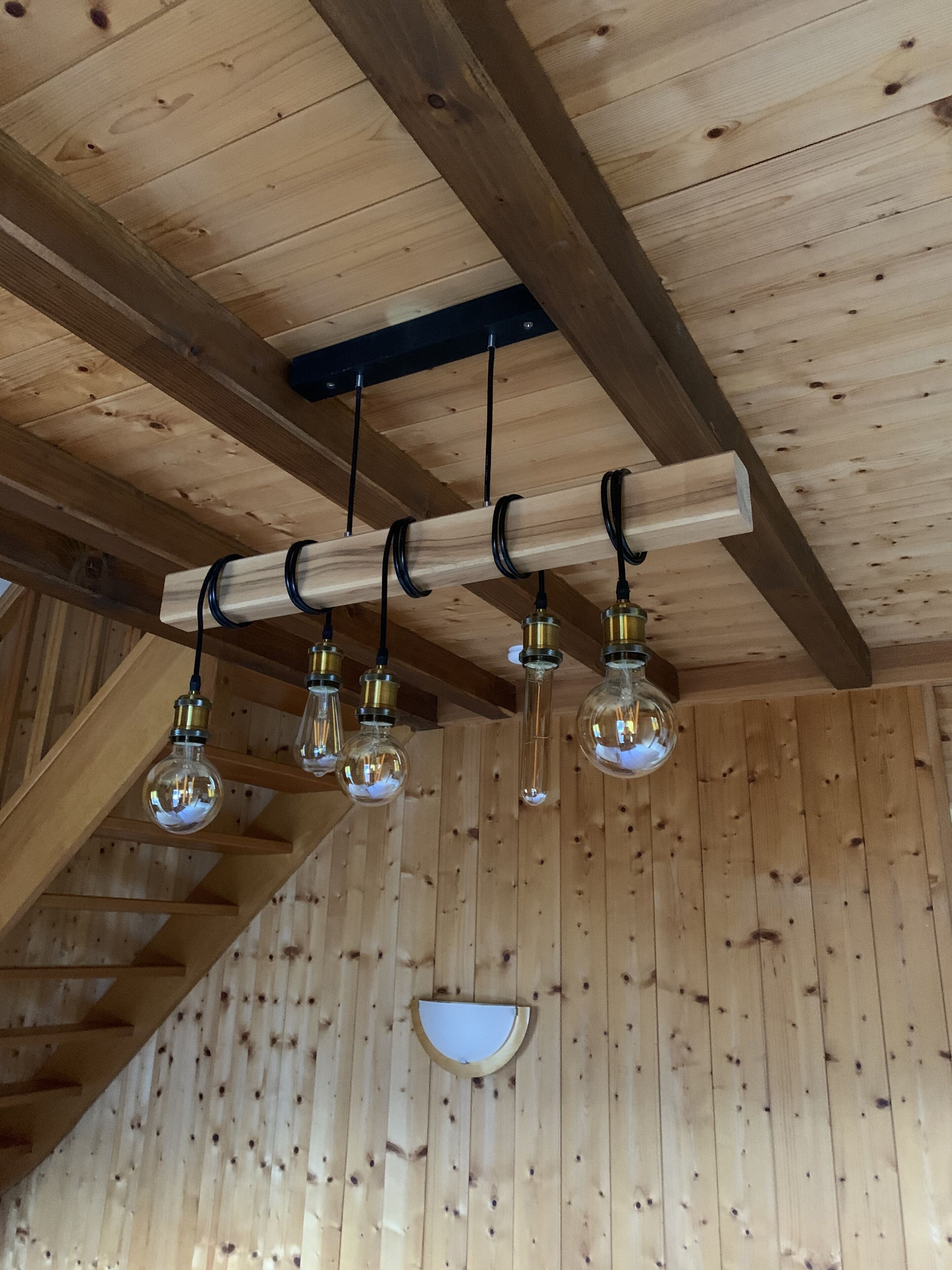 A wooden ceiling with exposed beams and a row of hanging light bulbs.