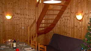 Un interior de madera con una mesa para dos, una botella de vino y dos sillas.