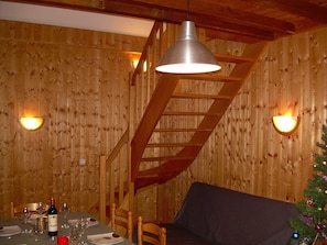 A dining area with a high staircase, pendant light, and a beautifully set table.