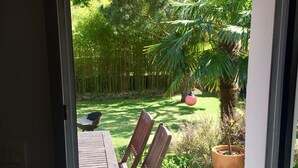 A wooden deck with a red umbrella, a table, and chairs.