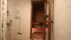 A small, tiled bathroom with a shower, a wooden bench, and a mop. - Jääskän Loma Ratatie Apartments Kauhava (Kauhava)