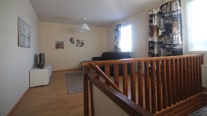 A spacious living area with a wooden staircase, a white cabinet, and a black sofa. - Jääskän Loma Ratatie Apartments Kauhava (Kauhava)