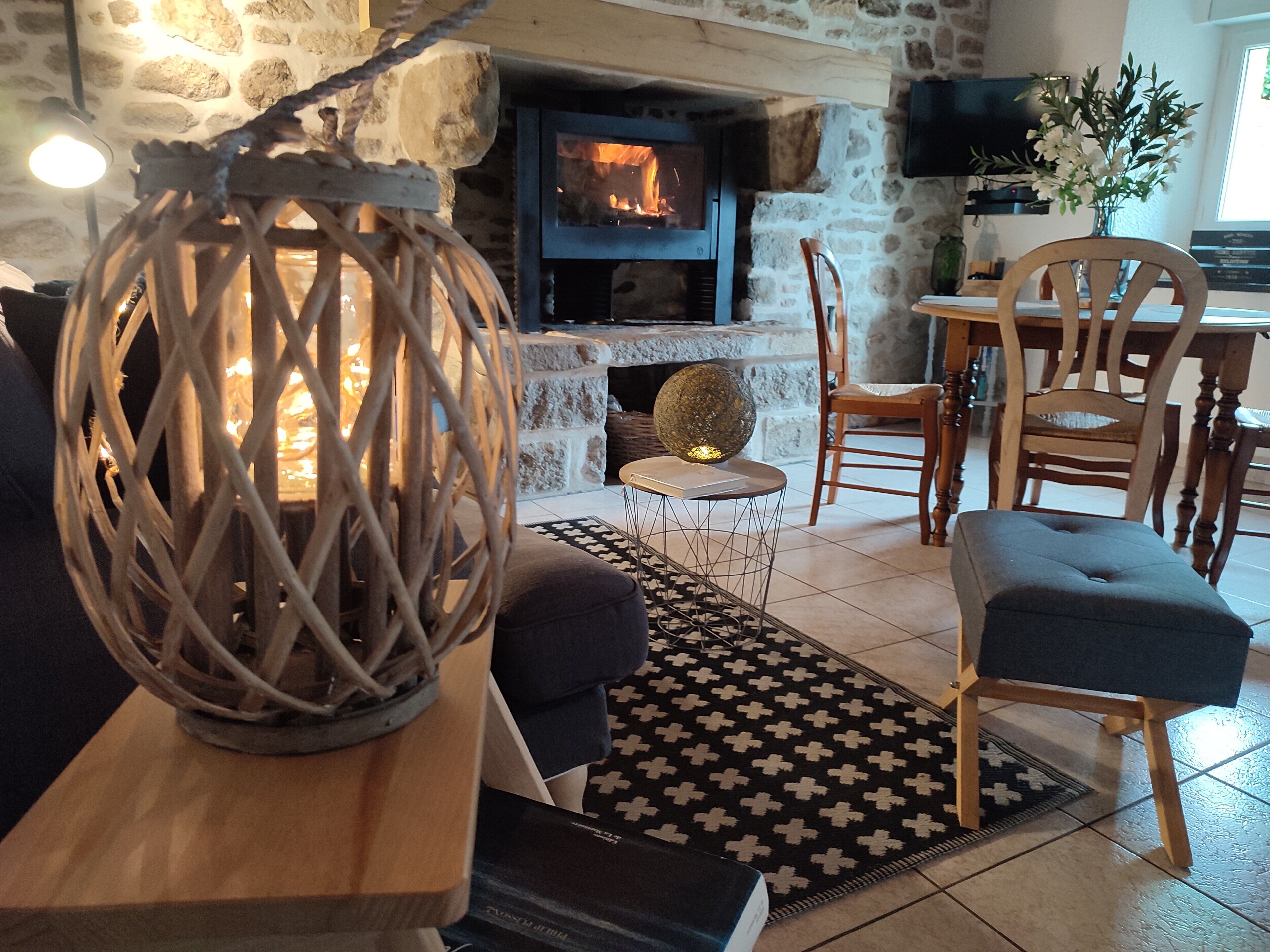 A cozy living room with a stone fireplace, wooden furniture, and a decorative lantern.