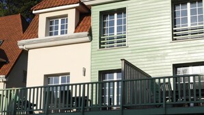 Ein zweistöckiges Haus mit grüner Fassade und einem roten Ziegeldach.
