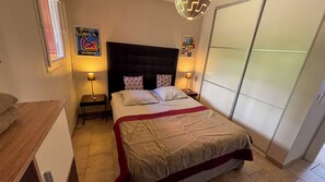 A bedroom with a bed, bedside lamps, a headboard, a poster on the wall, and a wardrobe.