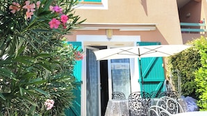 A two-story building with a balcony, a door with a glass panel, and a patio area with a table and chairs. - Vacation home 2 bedrooms, inner courtyard, seaside, 5 places max WiFi parking (Torreilles)
