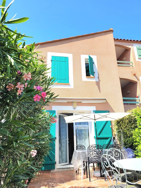 A two-story building with a balcony, a door with a glass panel, and a patio area with a table and chairs. - Vacation home 2 bedrooms, inner courtyard, seaside, 5 places max WiFi parking (Torreilles)