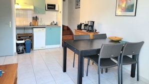 A compact kitchen with a microwave, toaster, and coffee maker. There is a dining table with chairs and a small wooden table with a bowl. - Vacation home 2 bedrooms, inner courtyard, seaside, 5 places max WiFi parking (Torreilles)