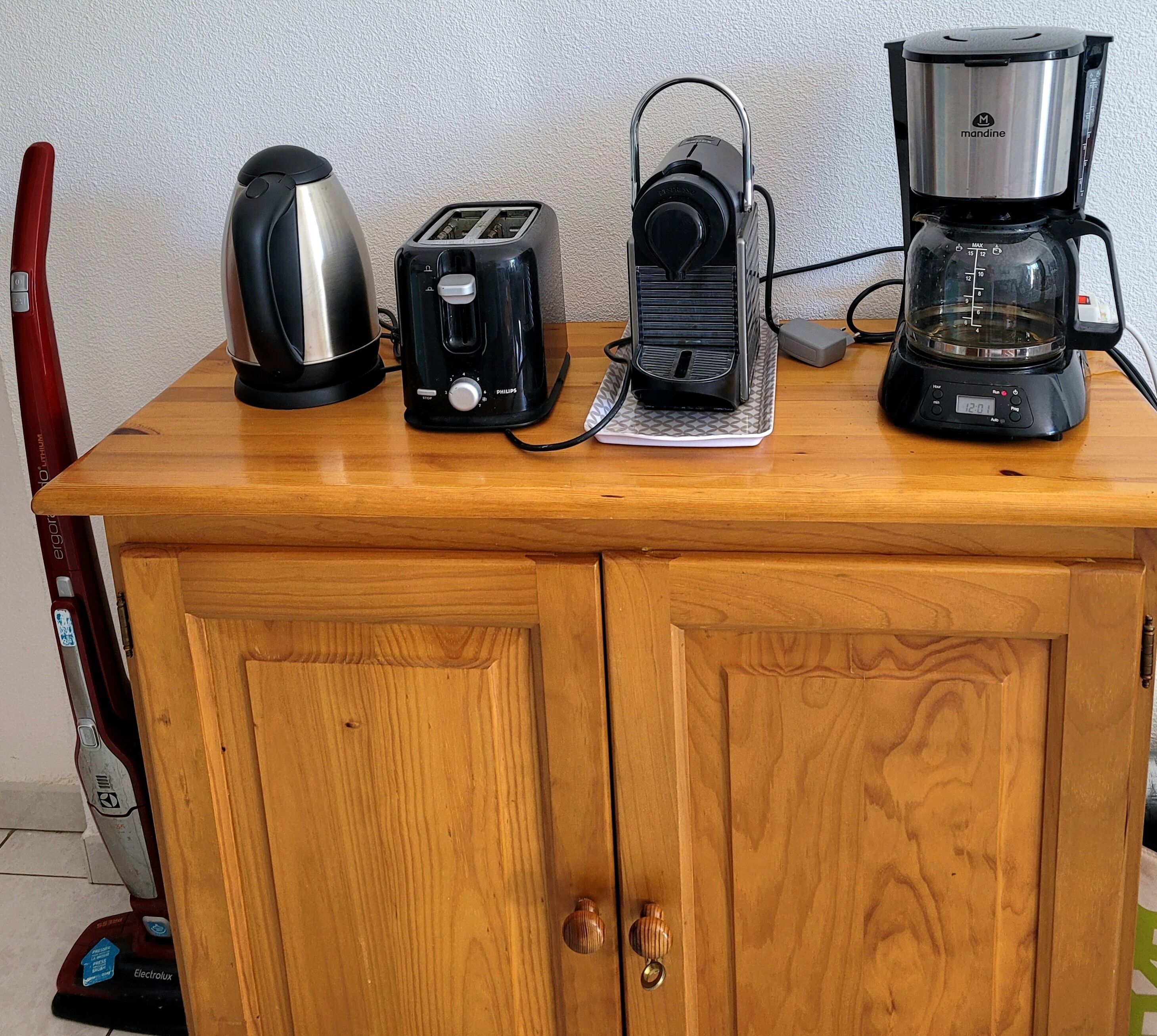 A wooden kitchen counter with a toaster, a coffee maker, and a kettle.