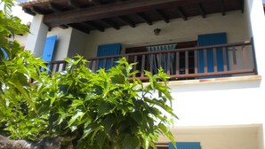 Un bâtiment doté d’un balcon, d’un toit en tuiles et de volets bleus.