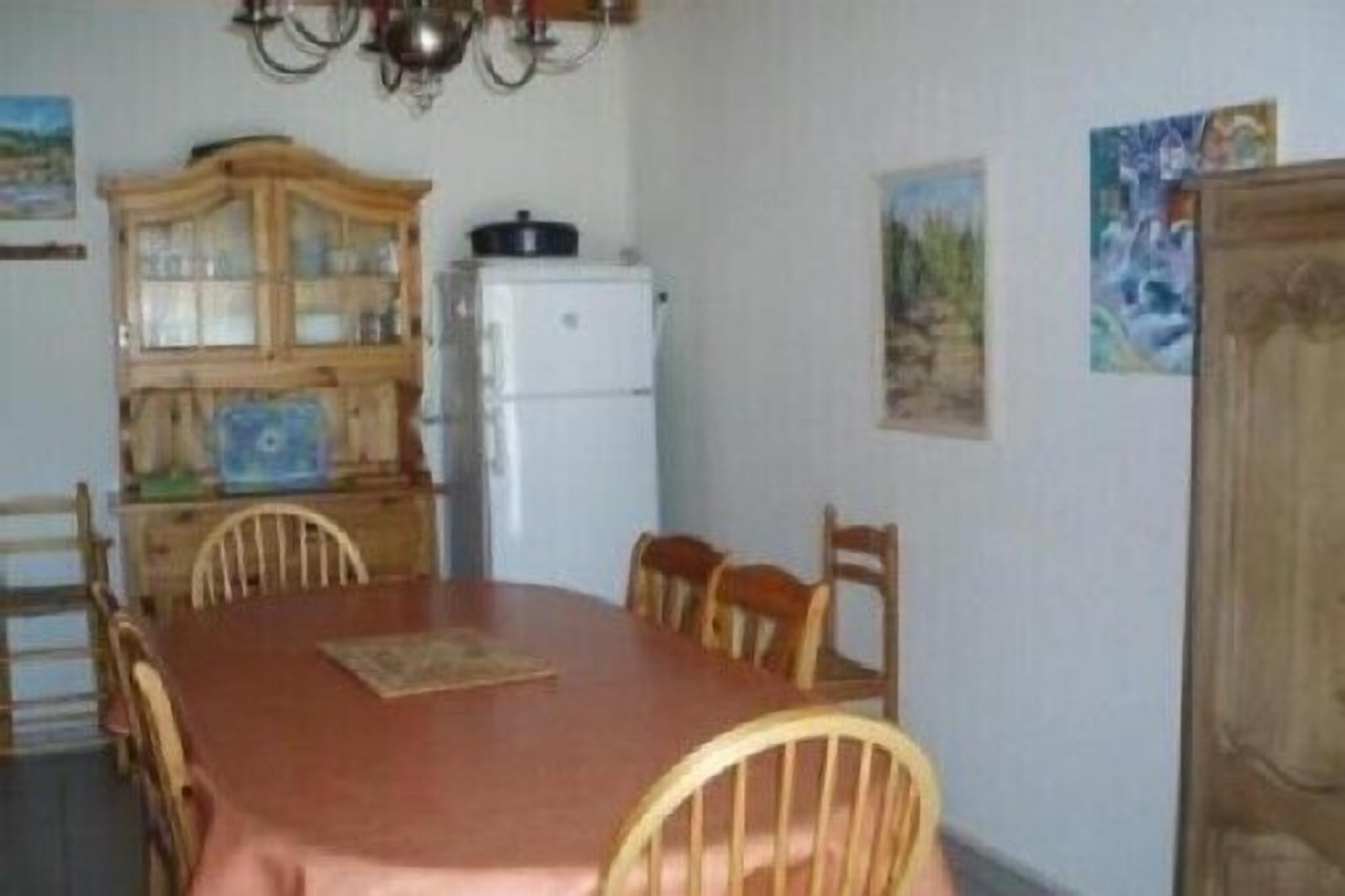 Ein Esszimmer mit Holztisch und Stühlen, einem Kühlschrank und einer Vitrine.