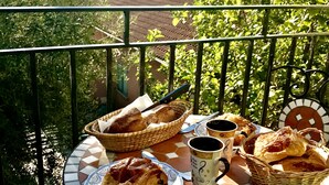 A balcony with a table set for breakfast, including croissants, bread, and coffee, overlooking a coastal view. - Detached house, near the coast, in a quiet area on the outskirts of BASTIA (Ville-Di-Pietrabugno)