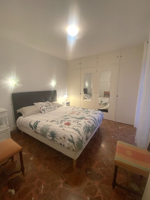 Une chambre à coucher comprenant un lit, des tables de chevet, une chaise et une armoire.