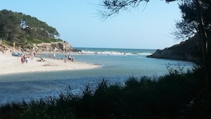 Una spiaggia con persone, cielo sereno e costa rocciosa.