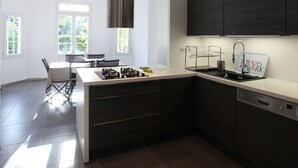 Een moderne keuken met donkere kastjes, een roestvrijstalen afzuigkap en een vaatwasser van Bosch.