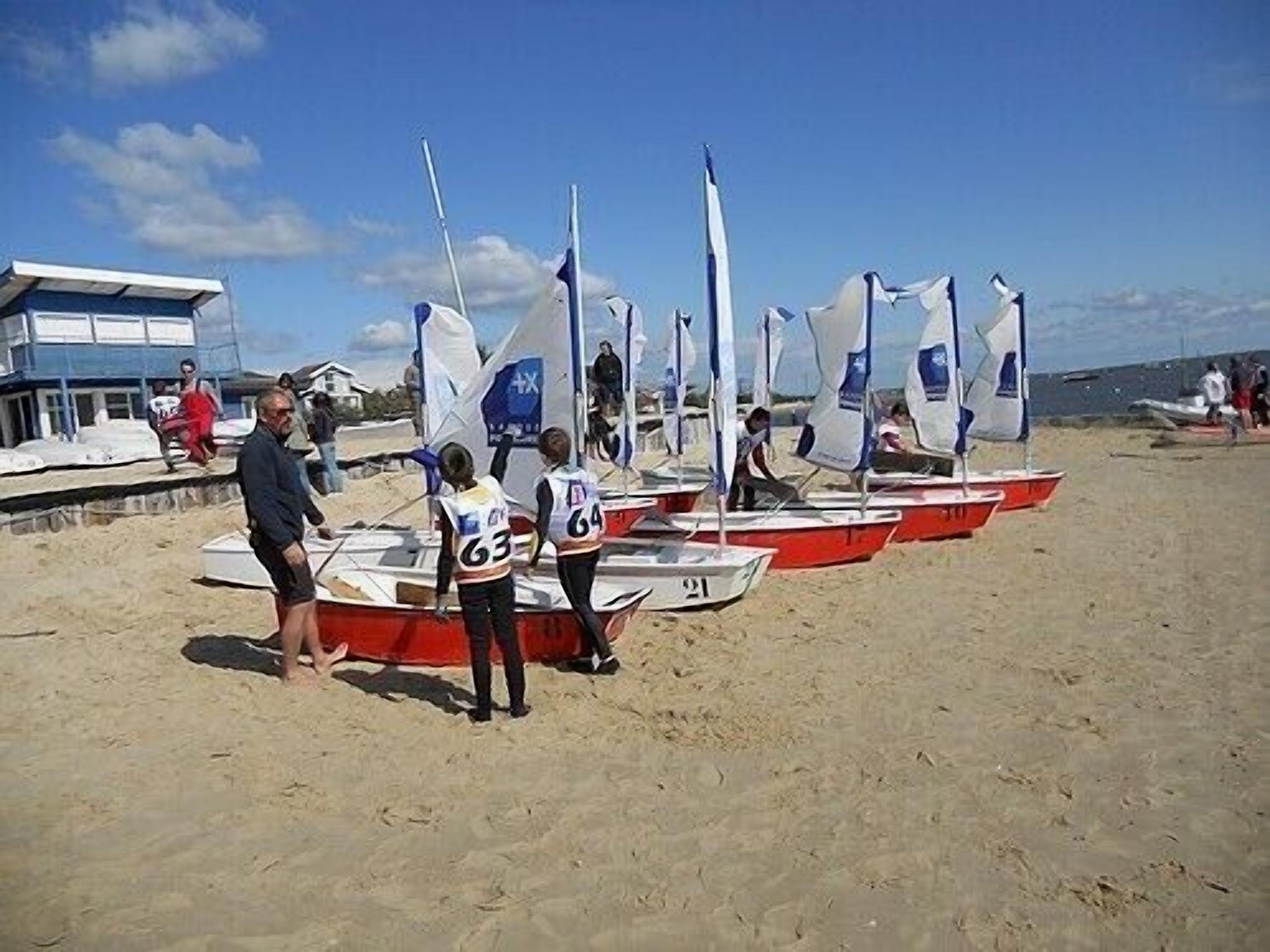 A beach with several small sailboats lined up.