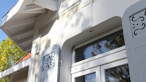 Een gebouw met een witte gevel, grote ramen en decoratieve ornamenten.