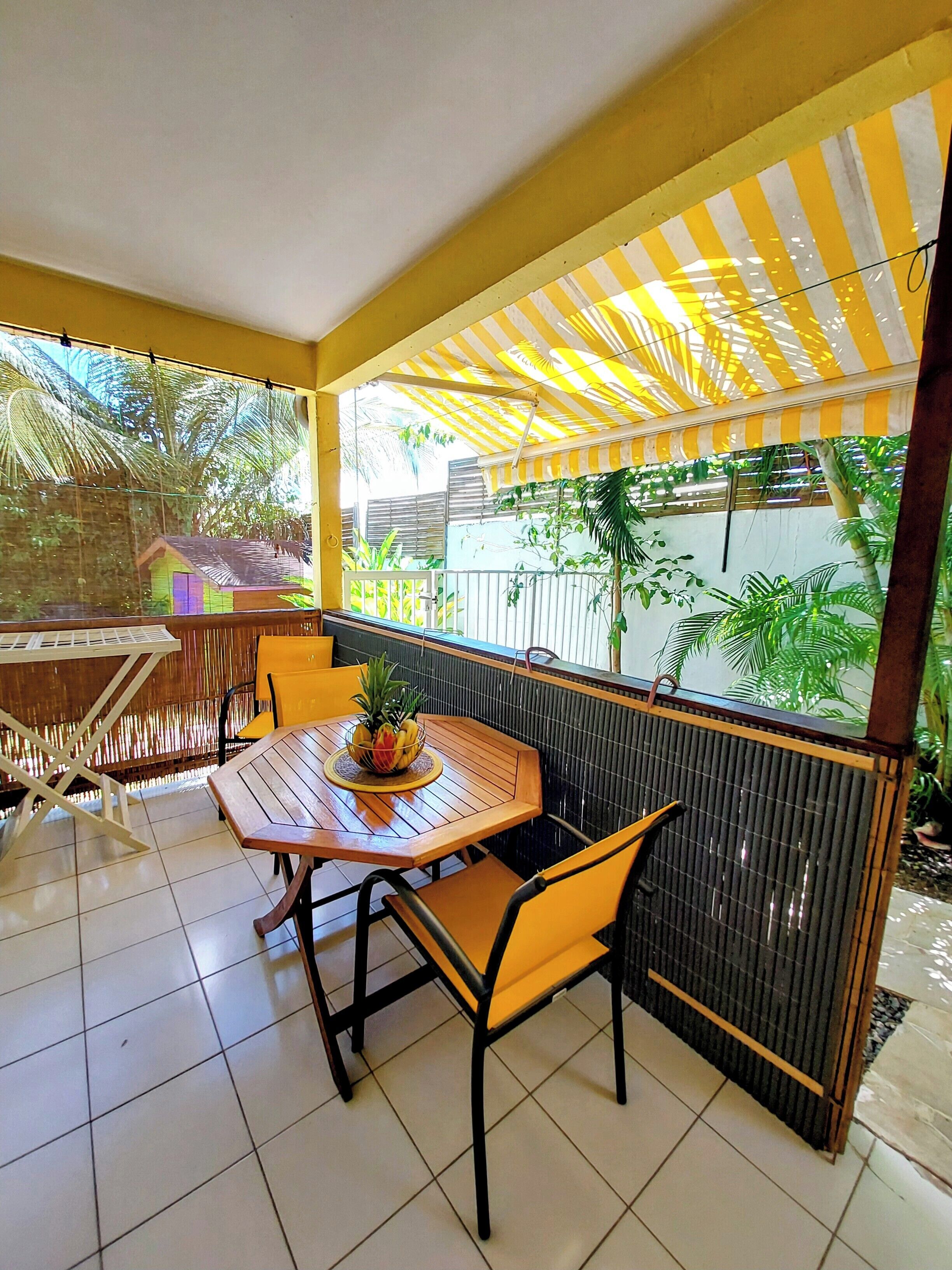 Un patio techado con mesa y sillas, un banco y vistas al exterior.