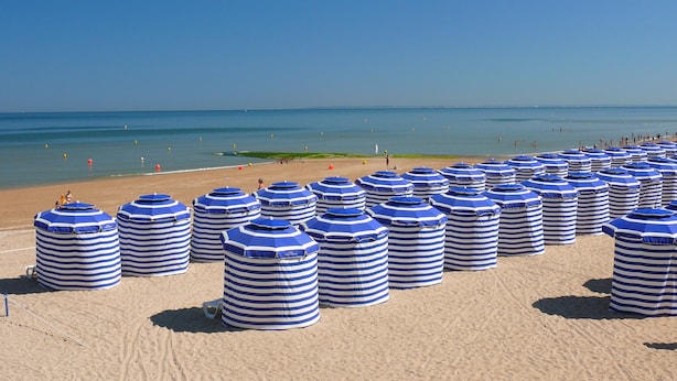 A beach with numerous striped beach umbrellas and a clear view of the ocean. - Beautiful renovated apartment - Walking distance to town and sea - Private parking (Cabourg)