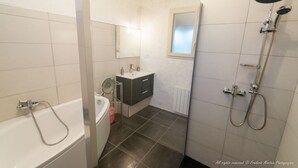 A bathroom with a bathtub, a shower, a sink, and a mirror.