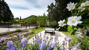 A pool area with lounge chairs, a table, and a stone wall.