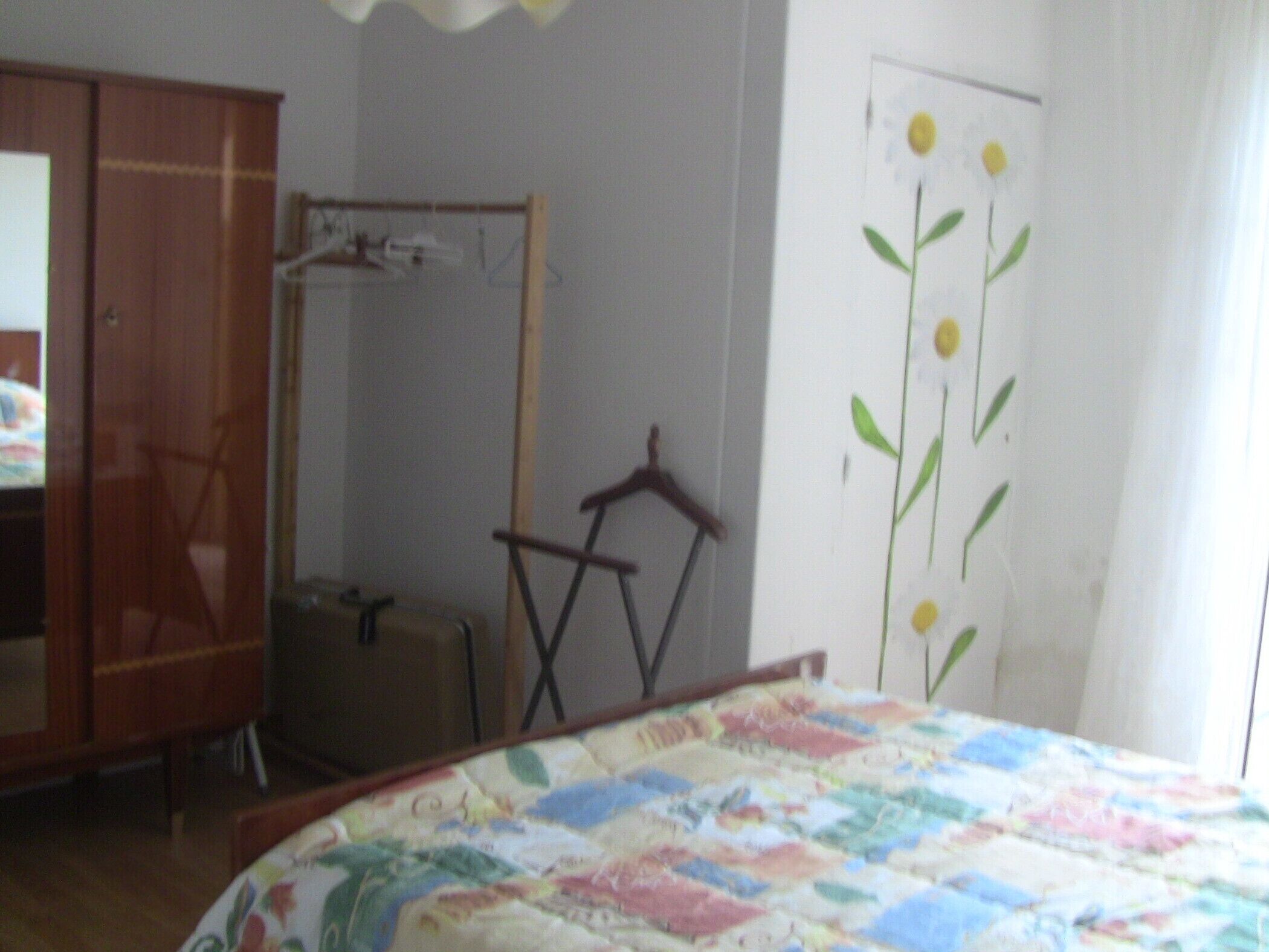 A bedroom with a bed, a wardrobe, a mirror, and a door with a floral decal.