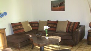 A living room with a brown leather sofa, patterned cushions, a small wooden coffee table, and a white flower vase. - RESTORED FARM LAND LEISURE & SON IN QUIET AT THE EDGE BRAYE (Savigny-Sur-Braye)