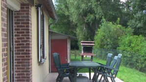A patio with a table and chairs, a brick wall, a red door, and a barbecue grill. - RESTORED FARM LAND LEISURE & SON IN QUIET AT THE EDGE BRAYE (Savigny-Sur-Braye)