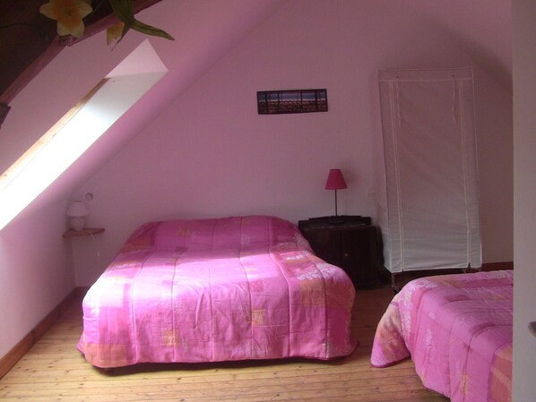 A bedroom with two beds, a nightstand, a lamp, and a window with a view.