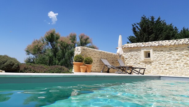 A pool area with a stone building, lounge chairs, and potted plants. - Charming house in Provence swimming pool and exceptional view (Forcalquier)
