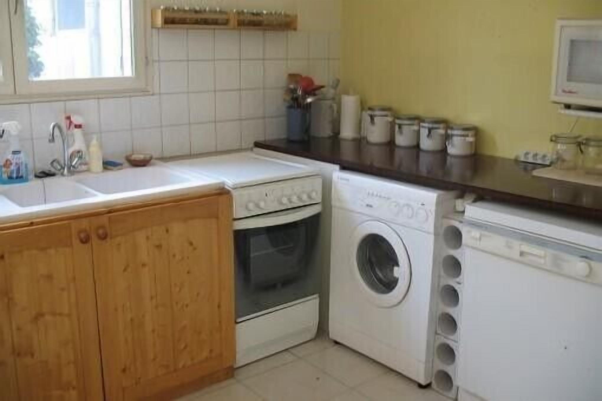 Una cocina con armarios de madera, lavadora, lavavajillas y microondas.