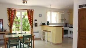 A compact kitchen with a dining area, a washing machine, and a small bar counter.