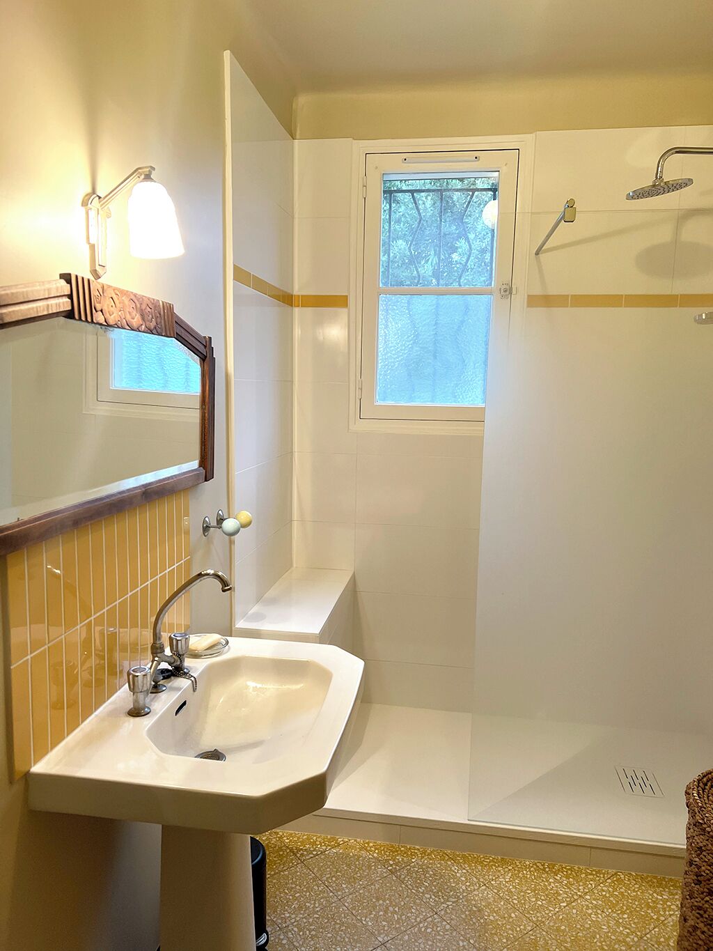 Un bagno con lavandino, specchio, finestra e doccia.