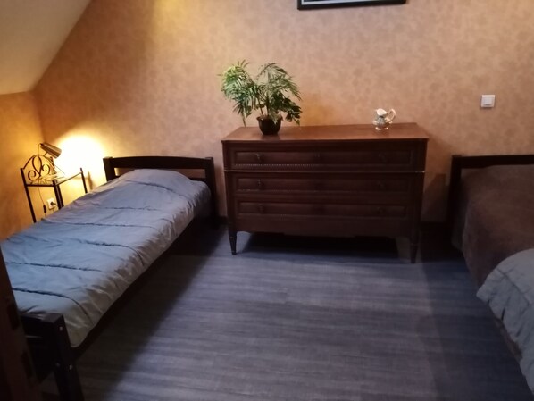A bedroom with a bed, a dresser, a nightstand, and a potted plant.