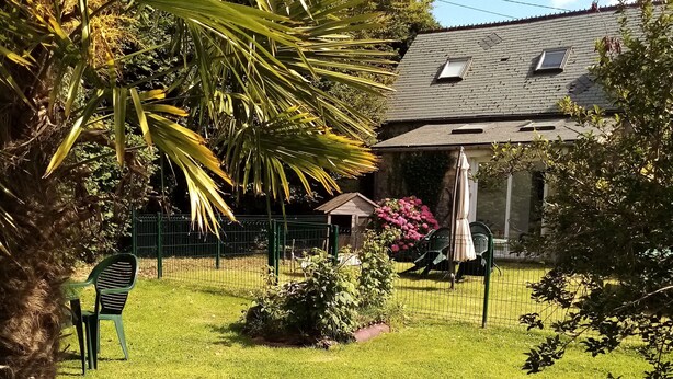Un césped con un edificio pequeño, una zona cercada y una silla.
