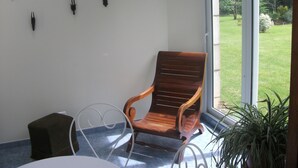 Una habitación con una silla de madera, una mesita y una planta en maceta.