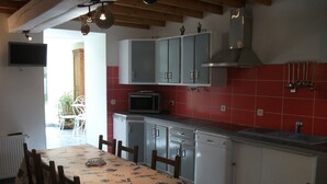 Una cocina con armarios blancos, microondas y un salpicadero de azulejos rojos.