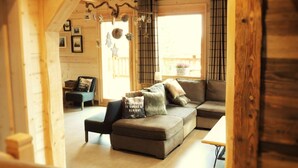 A cozy wooden interior with a sectional sofa, a small table, and a chair.