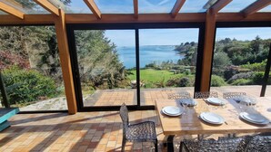 Comedor con una mesa preparada para cuatro, ventanas amplias y vista al mar.