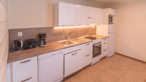 A modern kitchen with white cabinetry, a countertop with a coffee maker, a sink, and a dishwasher. - Jääskän Loma Kojola Apartments Alahärmä (Kauhava)