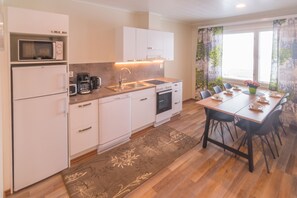 A modern kitchen with white cabinets, a microwave, a coffee maker, and a dining area with a table and chairs.