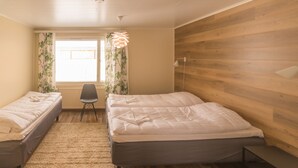 A bedroom with two beds, a wooden wall, a window with curtains, a chair, and a hanging light fixture. - Jääskän Loma Kojola Apartments Alahärmä (Kauhava)