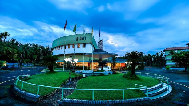A hotel with a circular central building, surrounded by a landscaped area with palm trees and a fountain. - Hyde Park (Ernad)