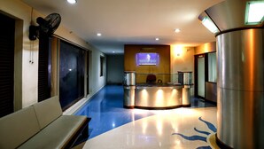 A reception area with a reception desk, a bench, and a wall-mounted fan. - Hyde Park (Ernad)