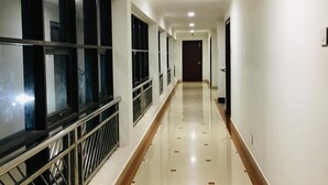 A long, well-lit corridor with a tiled floor, metal railings, and a series of doors at the end. - Hyde Park (Ernad)