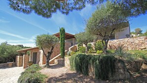 Un edificio in pietra con tetto in tegole, circondato da alberi e arbusti.